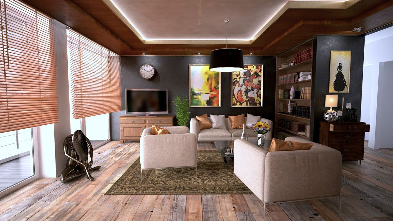 A single, sealed cardboard moving box sits in the middle of a sunlit, empty room with hardwood floors, symbolizing the transition of an empty nest.