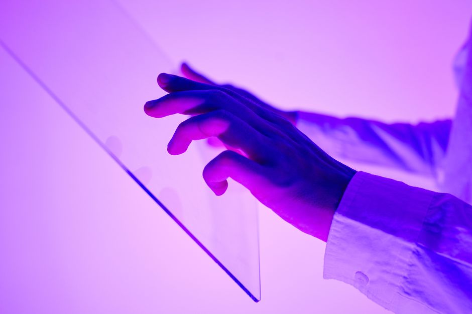 Professional architect thoughtfully interacting with a large, glowing digital interface in a modern, brightly lit office, ...