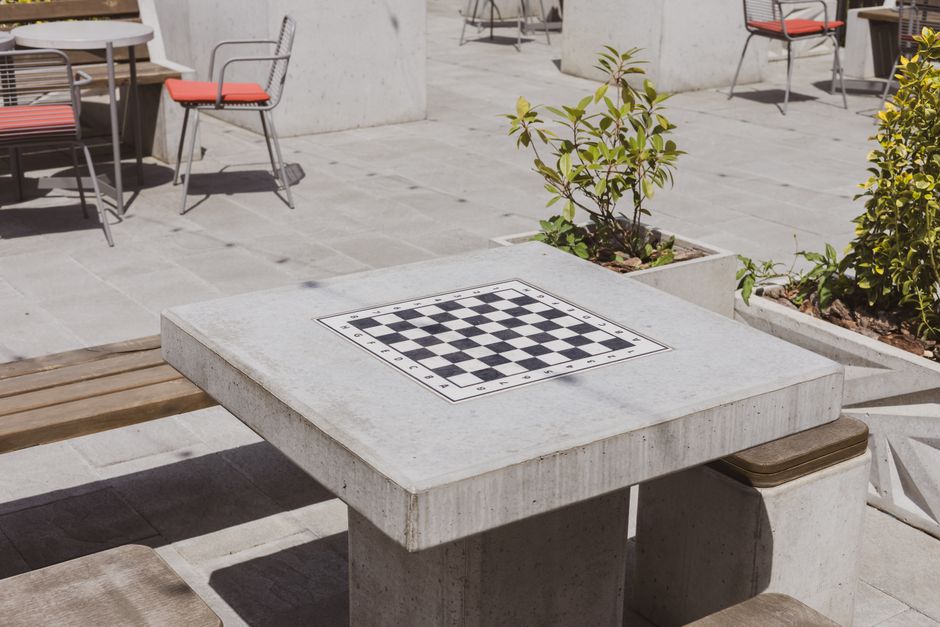 A sleek, modern chess board sits on a clean desk, with one piece moved forward, representing strategic thinking and calculated decision-making in a professional setting.